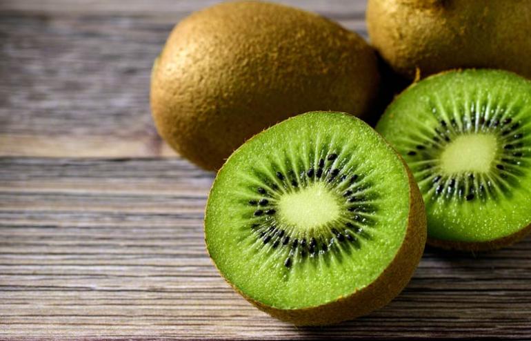 Cut a kiwifruit in half, then scoop out the flesh with a spoon