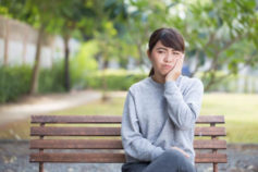 girl on park bench holding her jaw