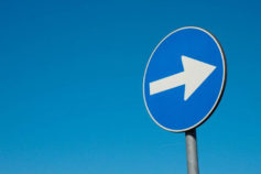 blue road sign with white arrow