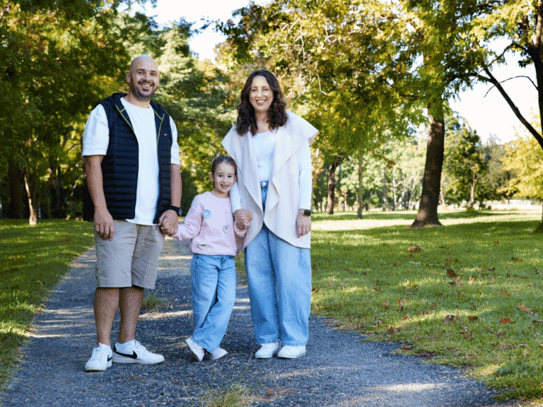 Family of three walking in a sunny park.