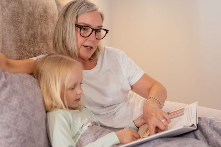 Grandmother reading a book with her young granddaughter.